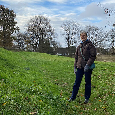 Foto: Mette Nørregaard Christensen står i porten i Danevirke. Porten er den som handlende, rejsende, fattige og rige, konger med følge og alle andre godtfolk har passeret. Et mægtigt anlæg på tværs af landet.